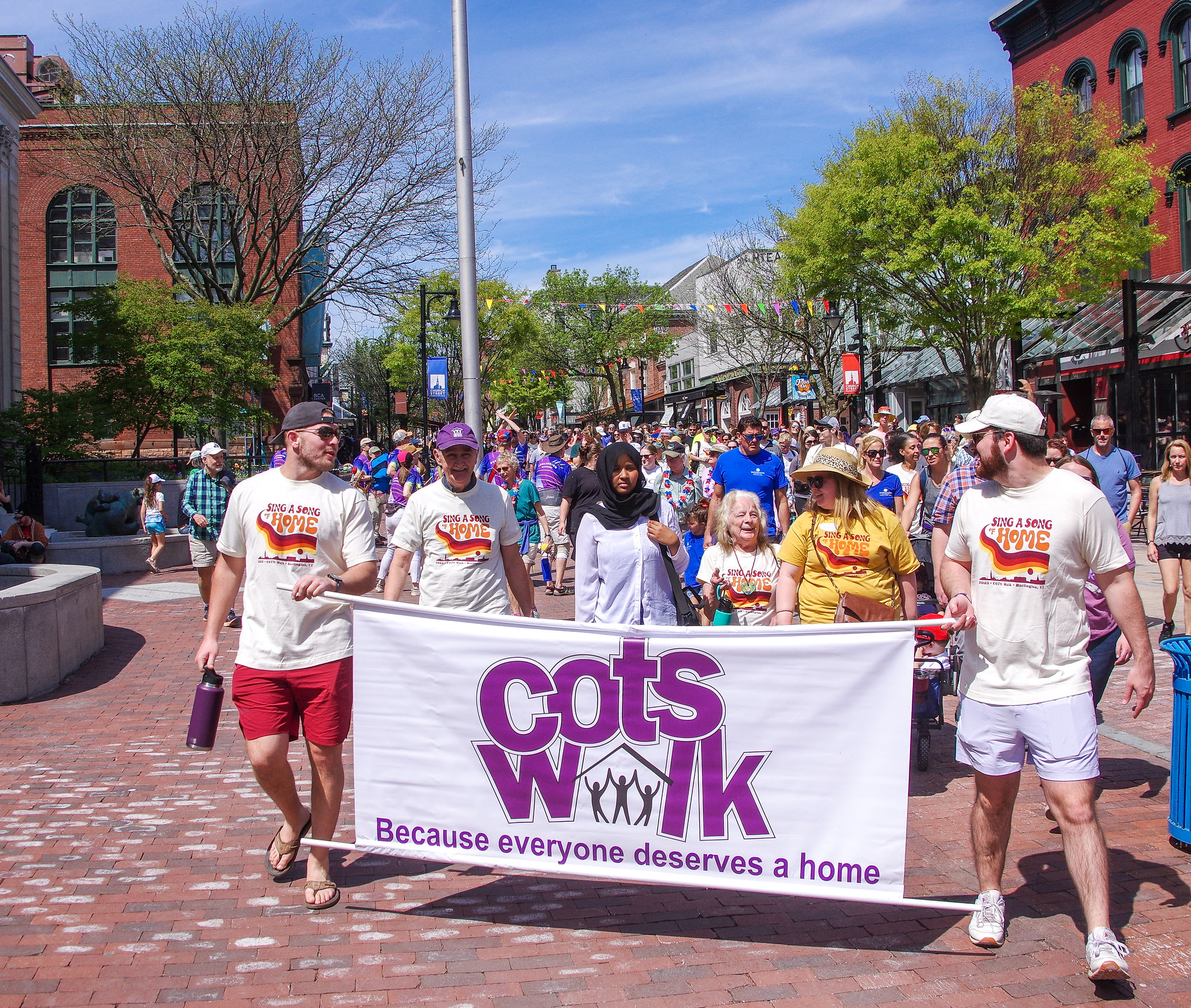Participants carrying a COTS banner during the 2023 COTS Walk down Church Street in Burlington, Vermont.