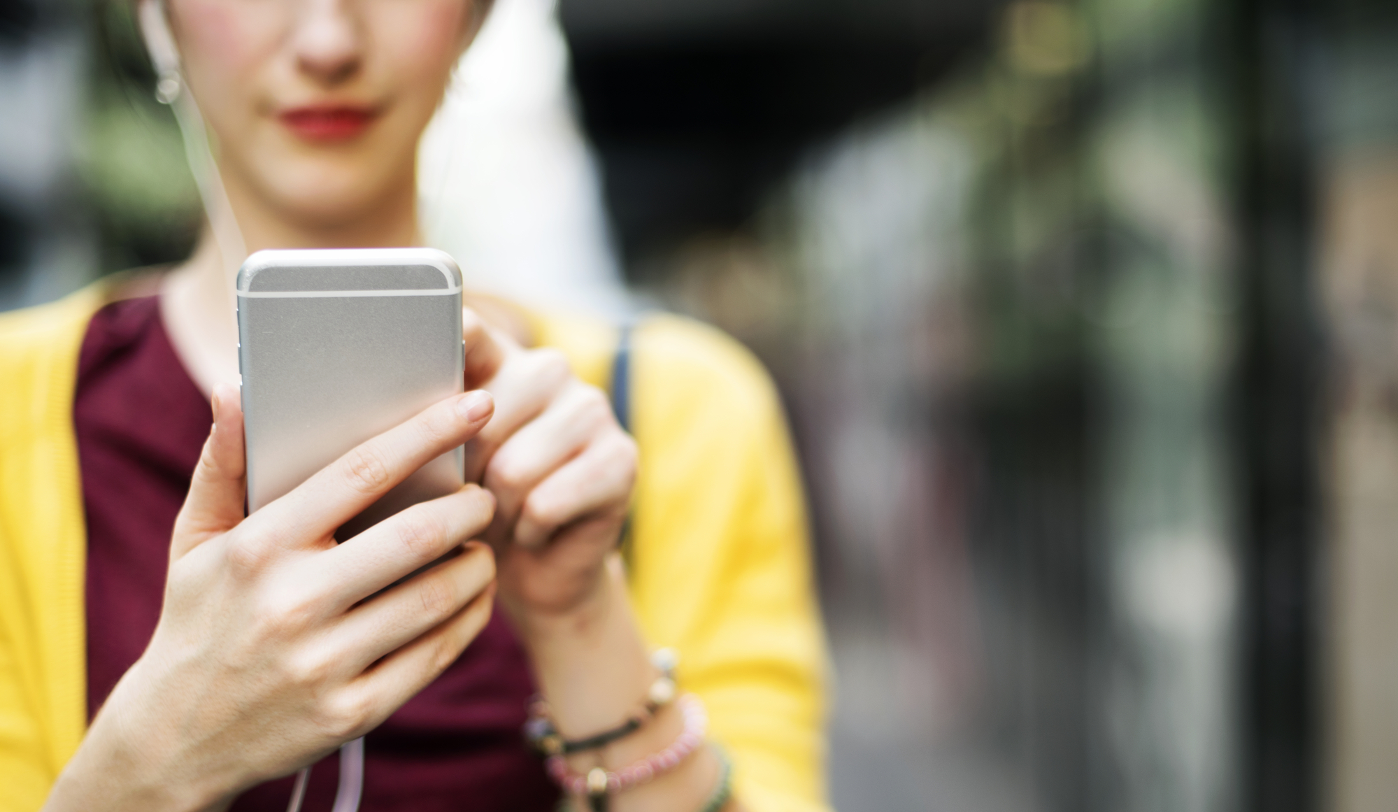 Cropped shot of a young woman using a mobile phone outside.